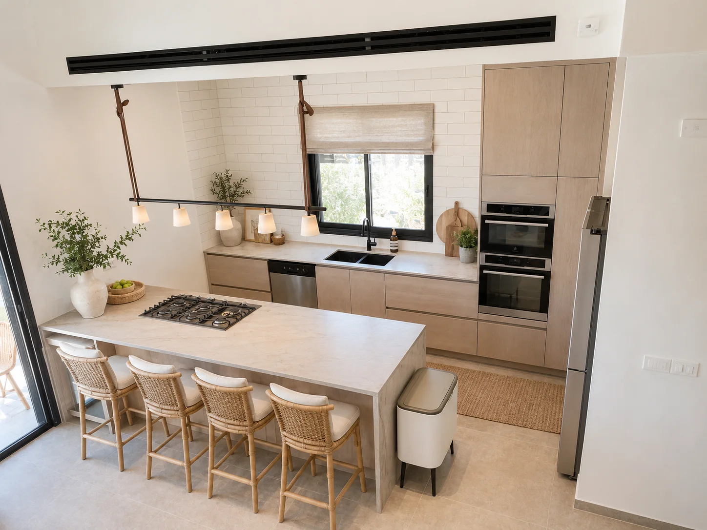 המטבח בעיצוב Coastal Modern בהיר עם עץ בגוון חול, כיסאות ראטן, טקסטיל לבן ומשטחי אבן בהירים